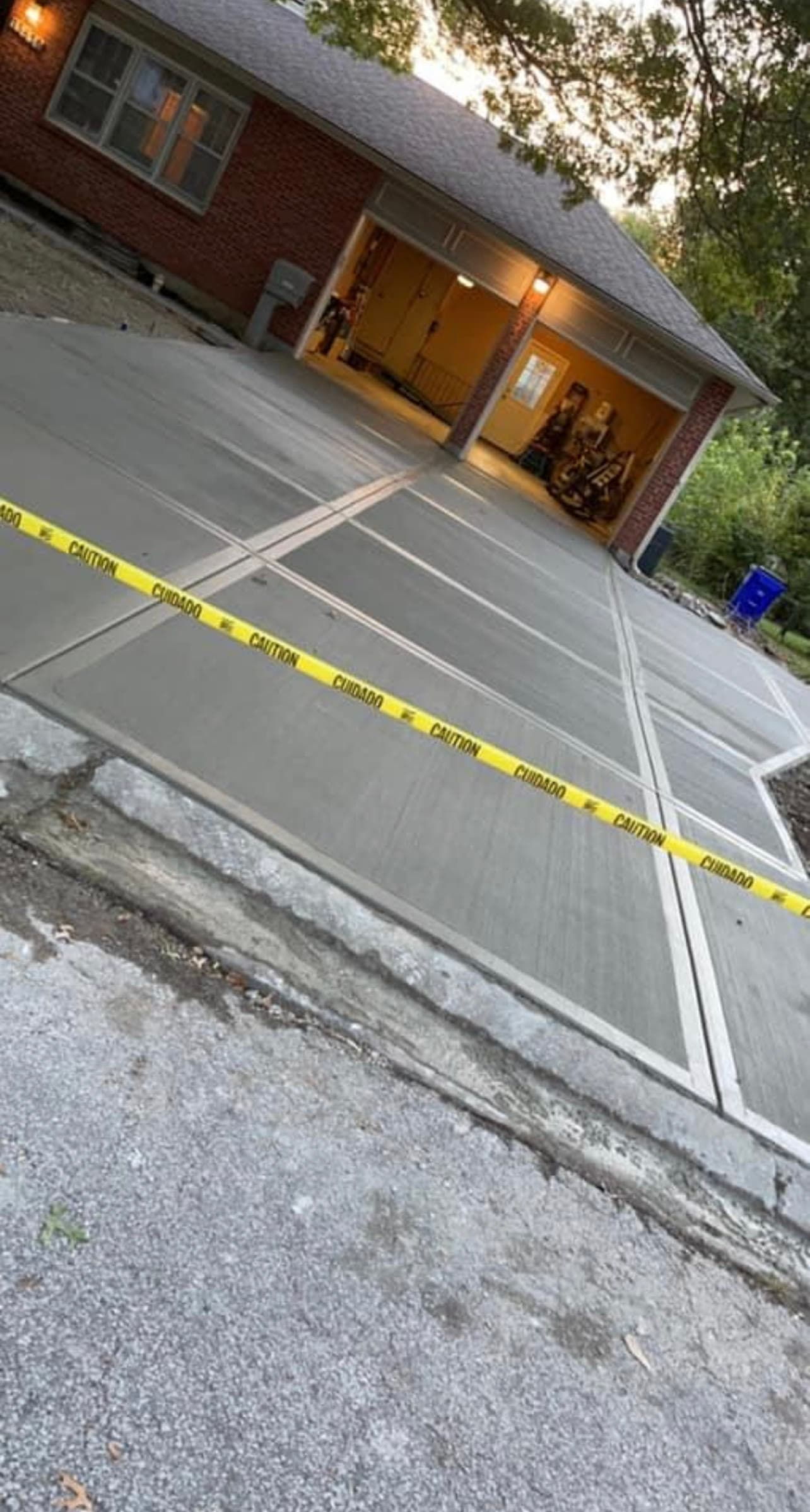 Freshly poured concrete driveway leading to a three-car garage at a brick home with an arched window