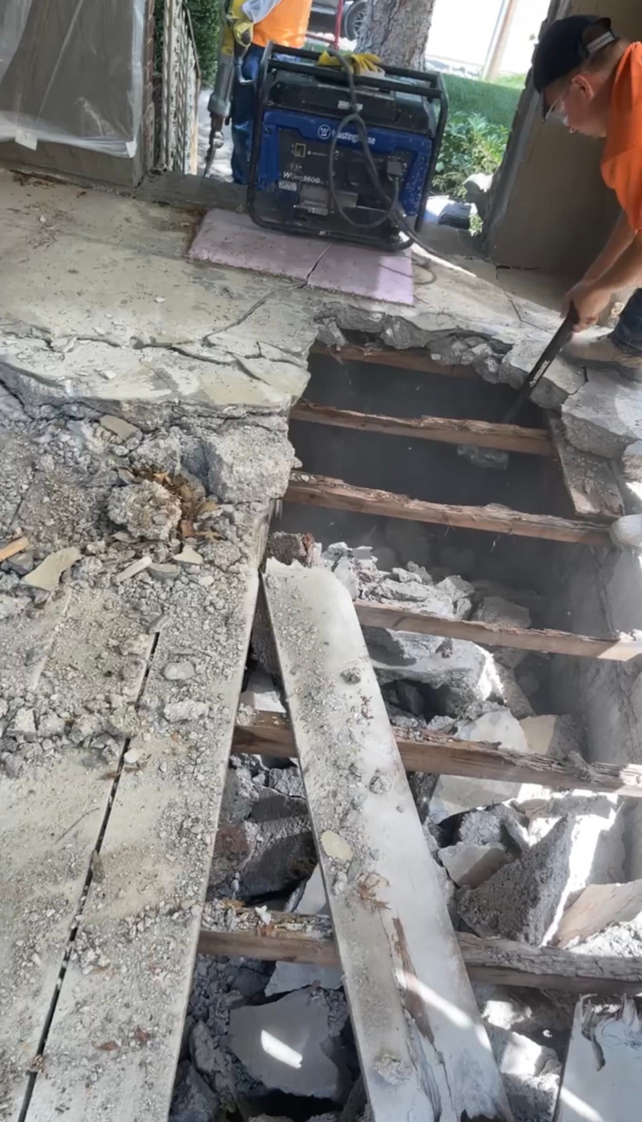Crew breaking up concrete during demolition, near the stoop area
