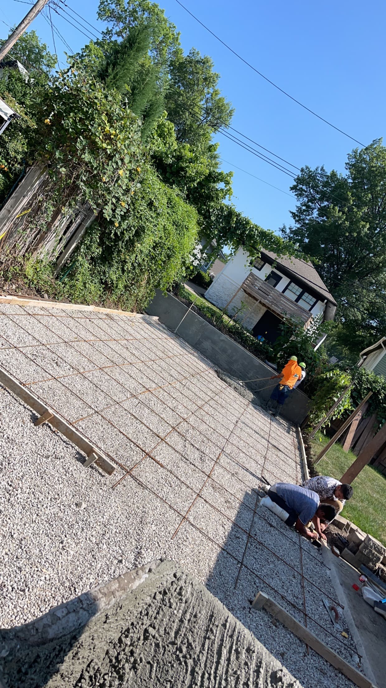 Rebar grid laid over a compacted gravel base for the driveway, with crew members tying reinforcement in the foreground