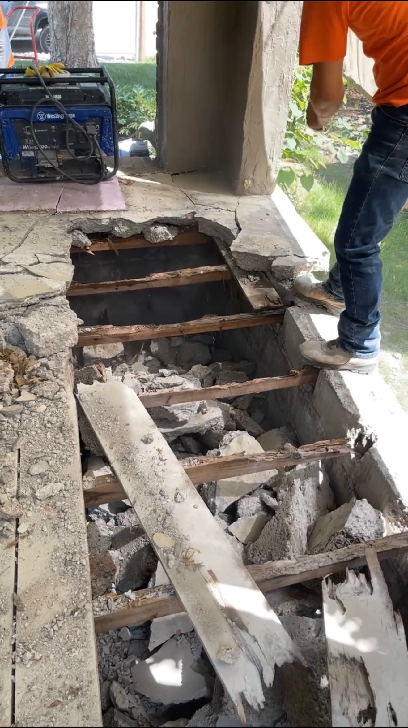 Open cavity beneath a stoop revealing wood supports and rubble, uncovered during demolition