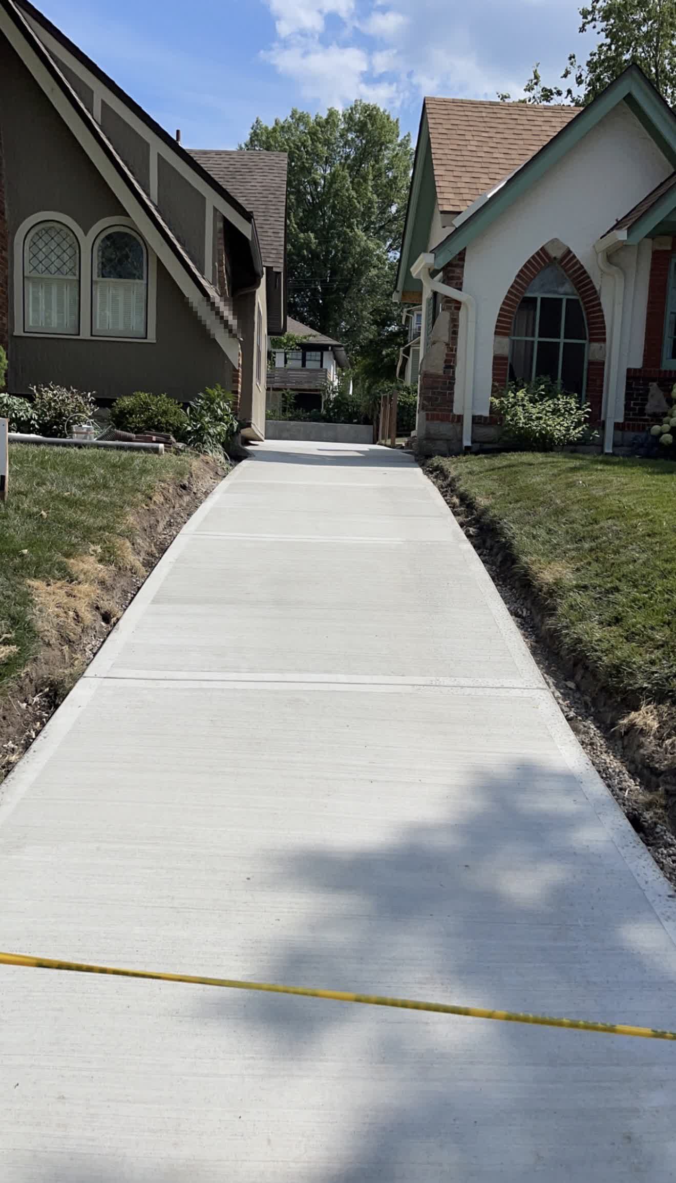 The same shared driveway after replacement, finished concrete running between both homes