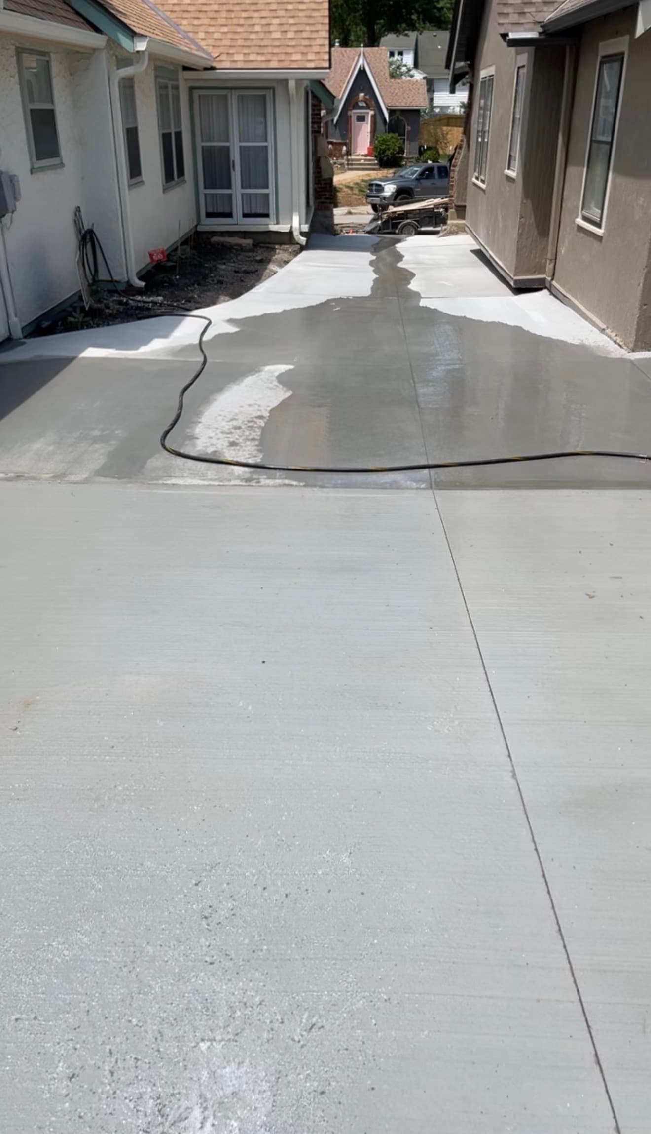 Water continuing to move across the finished driveway surface, away from the foundation edge